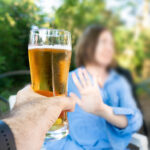 Hombre rechazando un vaso de cerveza con un gesto de mano, símbolo de sobriedad o negativa a beber alcohol