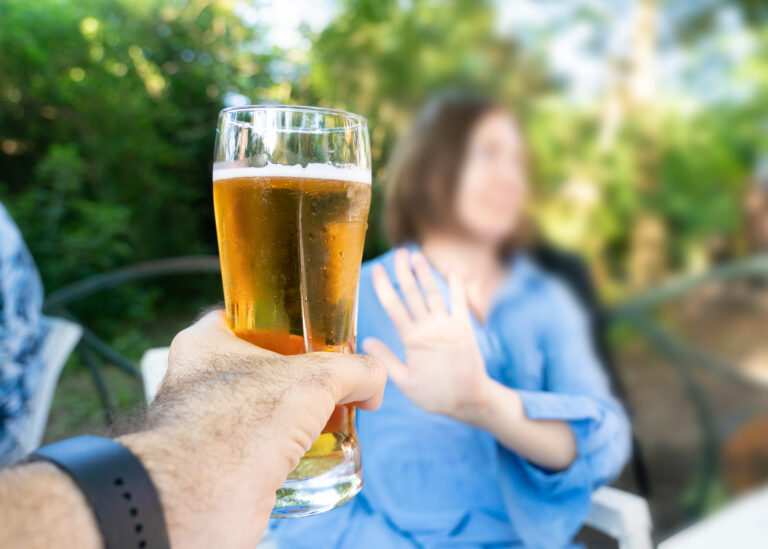 Hombre rechazando un vaso de cerveza con un gesto de mano, símbolo de sobriedad o negativa a beber alcohol
